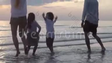 在晚上和日落一起度假的时候，快乐的亚洲家庭在海滩上跳跃和玩水
